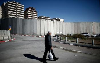 فلسطيني يمر قرب الجدار االذي يحيط بمخيم شعفاط