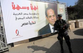 عسكري يقف بجوار صورة للرئيس المصري بغزة