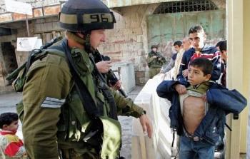 جندي إسرائيلي يفتش طفل فلسطيني