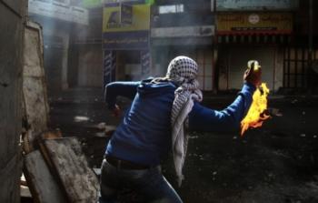 شاب فلسطيني يلقي زجاجة حارقة 