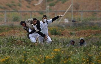 مسعفون يحملون جريحاً فلسطينيا على حدود غزة