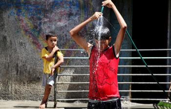 طفل يستحم بالمياه هربا من موجه الحر في غزة - APA