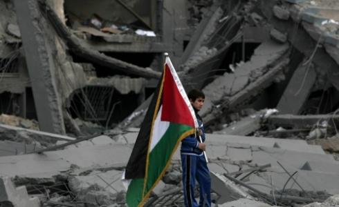 طفل يحمل علم فلسطين فوق أطلال منزله