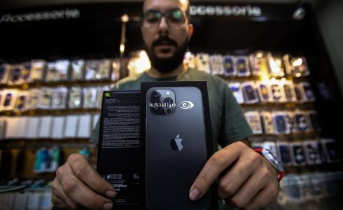 موظف من قسم التكنولوجيا في شركة سيتي فون يعرض جهاز أيفون 13 داخل معرض الشركة في مدينة غزة