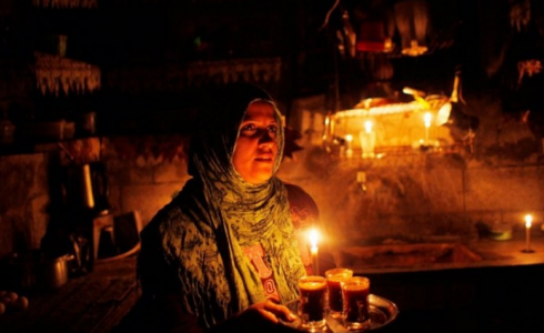 امرأة توقد شمعة بعد انقطاع التيار الكهربائي - تعبيرية