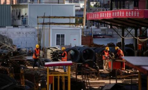 عمال يعملون في موقع بناء بعد تفشي فيروس كورونا في الصين