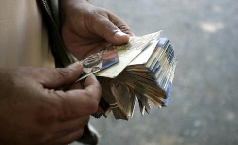 فلسطيني يقوم بعد عملة الشيكل والدولار في غزة