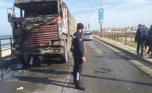 شرطي مرور يقف أمام شاحنة نقل احترقت على جسر وادي غزة