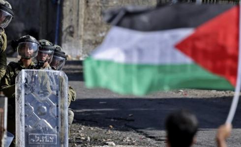 شاب يحمل علم فلسطين في مواجهة جنود الاحتلال