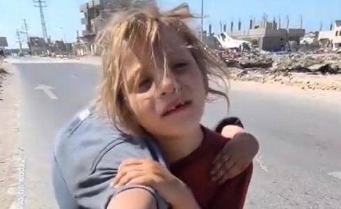 طفلة تحمل شقيقتها المصابة على كتفها