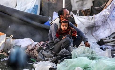 أي يحتضن طفله وسط الدمار في غزة - تعبيرية