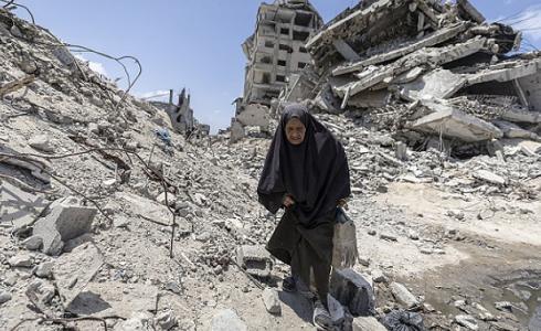 امرأة مسنة تمشي على الأنقاض الدمار في غزة - تعبيرية