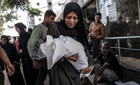 سيدة تحمل جثمان طفلها الرضيع الذي استشهد بغارة إسرائيلية على مدينة غزة، الشهر الماضي ( Getty Images)
