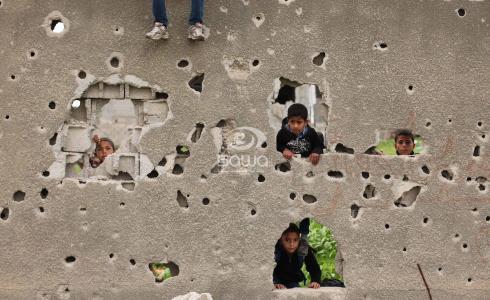 أطفال بغزة يقفون خلف جدار آيل للسقوط