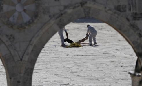 أفراد شرطة يرفعون جثة أحد الشهداء بالحرم، اليوم