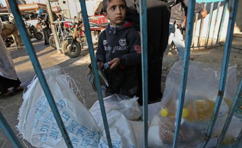 طفل يقف امام مركز توزيع اغذية تابع للاونروا بغزة