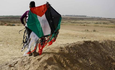 أحد المتظاهرين الفلسطينيين يمسك طائرة ورقية حارقة على حدود غزة
