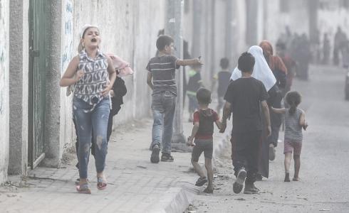 مواطنون يبتعدون عن مكان القصف الإسرائيلي الذي استهداف مبنى المسحال الثقافي في غزة أمس