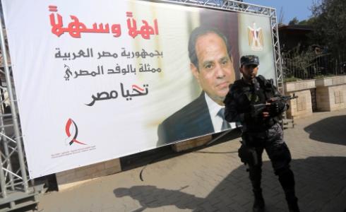 عسكري يقف بجوار صورة للرئيس المصري بغزة
