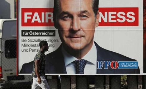 مهاجر أفريقي يمر جانب لافتة انتخابية