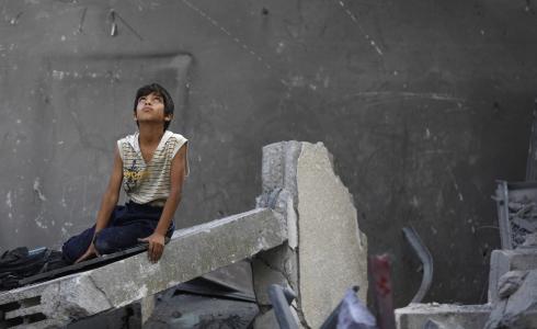 طفل من غزة يجلس على ركام أحد المنازل المدمرة