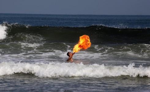 الشاب أبو حصيرة يقدم عروضا بالنار على شاطئ بحر غزة