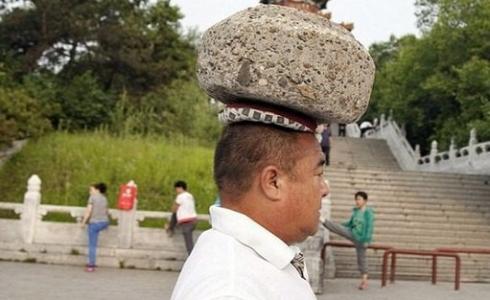 صينى يحمل حجراً بوزن 40 كيلوغراماً على رأسه 