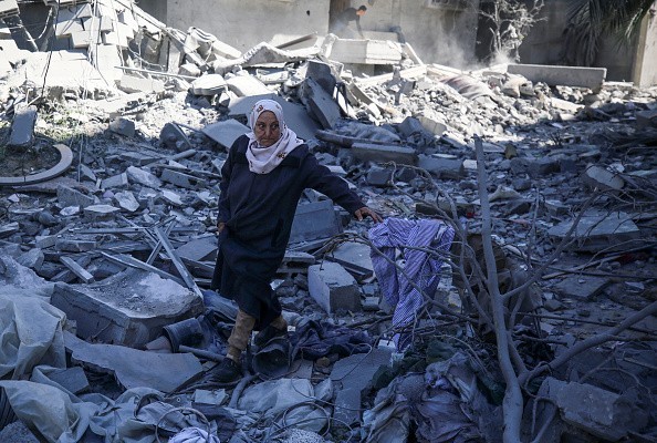 مسنة فلسطينية تقف على أنقاض منزل مدمر في قطاع غزة.jpg